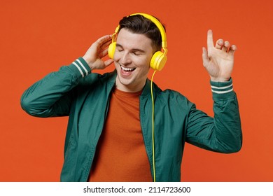 Cheerful fun magnificent satisfied young brunet man 20s wears red t-shirt green jacket listen to yellow headset headphones keep eyes closed dancing isolated on plain orange background studio portrait. - Powered by Shutterstock