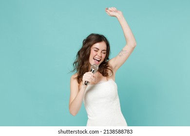 Cheerful Funny Bride Young Woman 20s Years Old In White Wedding Dress Sing Song In Microphone Dancing Isolated On Blue Turquoise Color Background Studio Portrait. Ceremony Celebration Party Concept