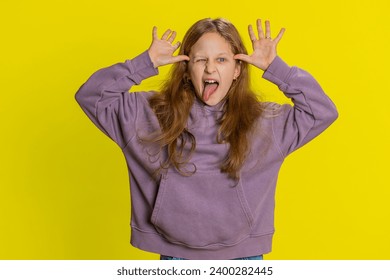 Cheerful funny bully young cute girl showing tongue making faces at camera, fooling around, joking, aping with silly face, teasing. Preteen redhead child kid on yellow background. Little children - Powered by Shutterstock