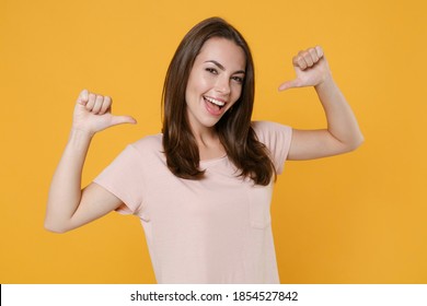Cheerful funny young brunette woman 20s wearing pastel pink casual t-shirt standing posing pointing thumbs on herself looking camera isolated on bright yellow color wall background studio portrait - Shutterstock ID 1854527842