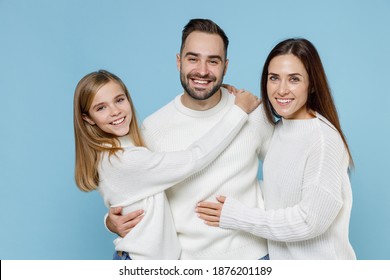 Cheerful Funny Young Happy Parents Mom Dad With Child Kid Daughter Teen Girl In Basic White Sweaters Hugging Isolated On Blue Color Background Studio Portrait. Family Day Parenthood Childhood Concept