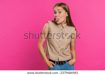 Cheerful funny young woman showing tongue making faces at camera, fooling around, joking, aping with silly face, teasing, bullying, abuse. Girl isolated alone on pink studio background. Lifestyles