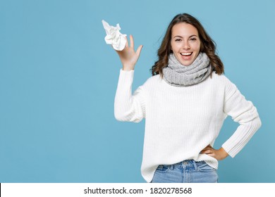 Cheerful Funny Young Woman Wearing White Sweater Gray Scarf Throwing Out Paper Napkin Isolated On Blue Background Studio Portrait. Healthy Lifestyle Ill Sick Disease Treatment Cold Season Concept