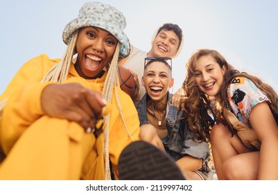 Cheerful generation z friends having fun together outdoors. Group of multiethnic friends smiling at the camera cheerfully. Vibrant young people making happy memories together. - Shutterstock ID 2119997402