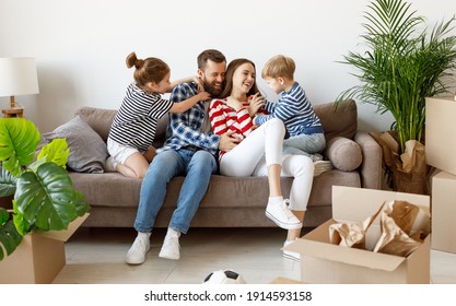 Cheerful girl and boy tickling laughing parents while resting on settee near cardboard boxes and plants in new apartment