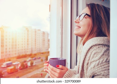 Cheerful Girl Drinking Coffee In Morning Sunlight In Open Window