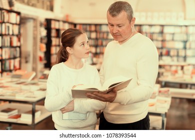 Cheerful girl with father choosing and discussing books in bookshop - Powered by Shutterstock