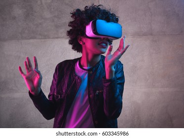 Cheerful girl with hands up wearing the virtual reality goggles.