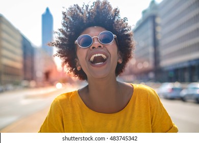 Cheerful girl laughs in the middle of a big avenue
