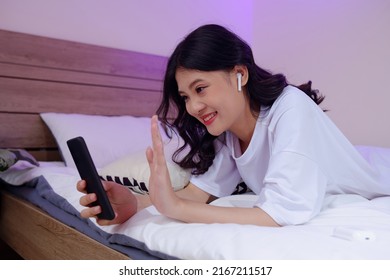 Cheerful Girl Wearing Earbuds When Video Calling Her Friend Or Family Member From College Dormitory