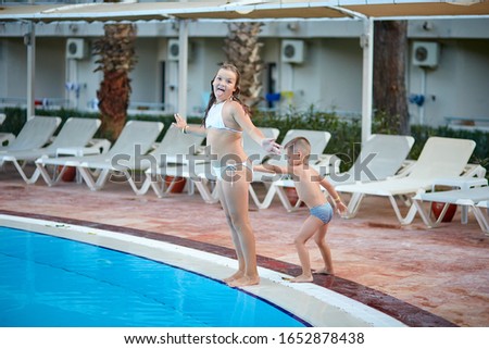cheerful girl in a white swimsuit jumps into the pool