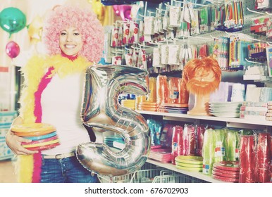 Cheerful Girl In A Wig Shows Things For A Party In A Store