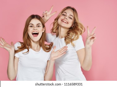 cheerful girlfriends on a pink background gestures with hands                             