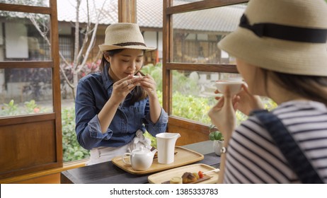 Cheerful Girlfriends Spending Time Together At Japanese Local Cafe Kyoto Talking And Laughing Happily. Young Girls Travelers Holding Tea Bowl Drink. Friendship Teenager Communication Diversity Relax