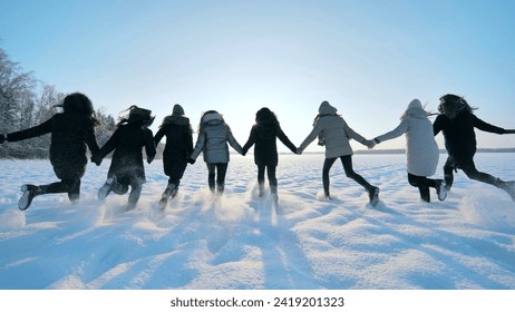 Cheerful girls run across the snow-covered field. - Powered by Shutterstock