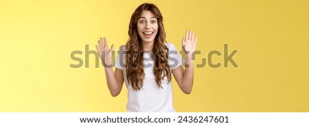 Cheerful glad outgoing cute positive young girl smiling broadly raise both palms waving hands hello greeting gesture welcome friend guest smiling hi gladly invite come inside yellow background