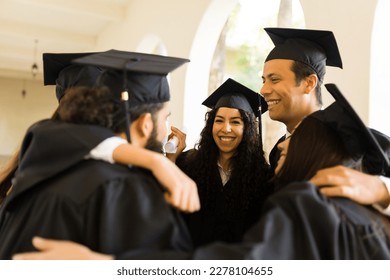 Cheerful graduates friends hugging in a circle and laughing while looking excited during their college graduation ceremony - Shutterstock ID 2278104655