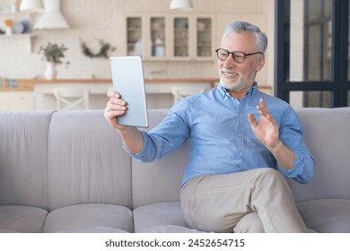 Cheerful grandfather mature senior caucasian man with grey hair having online video call zoom using digital tablet pad, talking with children, grandchildren ,calling his doctor. Active seniors life - Powered by Shutterstock