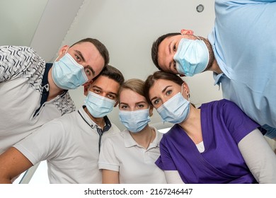 A Cheerful Group Of Dentists And Their Assistants Stand In The Dental Office And Smile Happily. The Concept Of Working Leisure For Physicians.