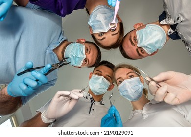 A Cheerful Group Of Dentists And Their Assistants Stand In The Dental Office And Smile Happily. The Concept Of Working Leisure For Physicians.