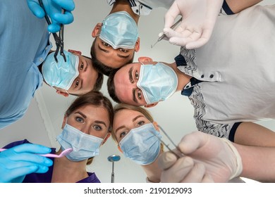 A Cheerful Group Of Dentists And Their Assistants Stand In The Dental Office And Smile Happily. The Concept Of Working Leisure For Physicians.