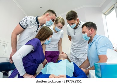 A Cheerful Group Of Dentists And Their Assistants Stand In The Dental Office And Smile Happily. The Concept Of Working Leisure For Physicians.