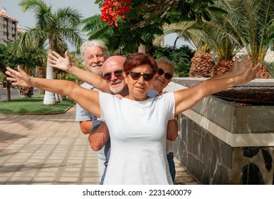 Cheerful group of four seniors in the park joking around lining up behind each other - concept of active and positive seniors during retirement - Shutterstock ID 2231400079