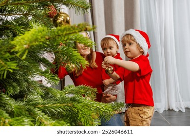 A cheerful group hangs decorations on a Christmas tree, each wearing a Santa hat and red t-shirt full of holiday spirit - Powered by Shutterstock