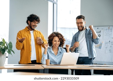 Cheerful group of motivated successful multiracial business people, working together on a project in a modern office, using laptop, discussing ideas, brainstorming, rejoicing in success, smile - Powered by Shutterstock