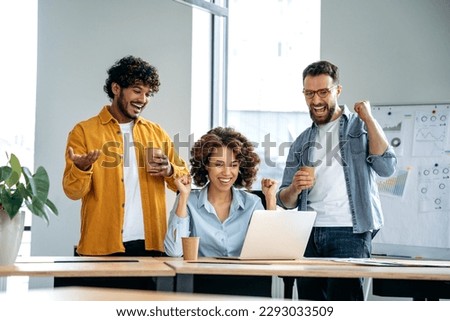 Cheerful group of motivated successful multiracial business people, working together on a project in a modern office, using laptop, discussing ideas, brainstorming, rejoicing in success, smile