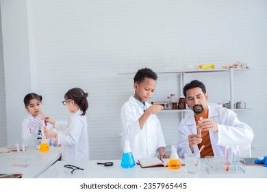 Cheerful group of Multicultural primary school students wearing lab coats studying with Indian teacher attention to experiment test tube in laboratory room, lifestyle learning education science class - Powered by Shutterstock