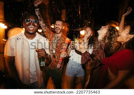 A cheerful group of people rejoices at the roof open-air nightclub and throws confetti. People are drinking, dancing and having a good time at the party. Stock photo © 