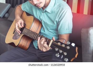 Cheerful Guitarist. Cheerful Handsome Young Man Playing Guitar Sitting At Room