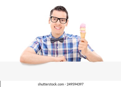 Cheerful Guy Holding An Ice Cream Behind A Panel Isolated On White Background