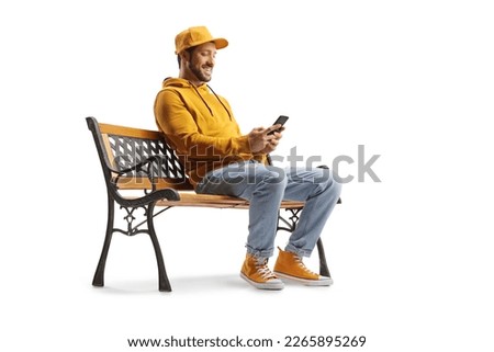 Cheerful guy sitting on a bench and using a smartphone isolated on white background