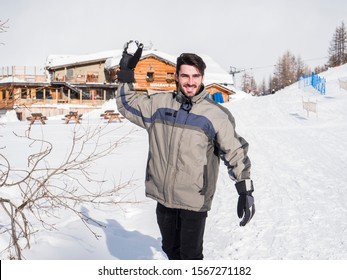 Cheerful Handsome Man In Outerwear Throwing Snowball Posing At Camera In Sunlight.