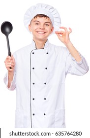 Cheerful Handsome Teen Boy Wearing Chef Uniform. Portrait Of A Happy Cute Male Child Cook With Black Ladle, Isolated On White Background. Food And Cooking Concept.