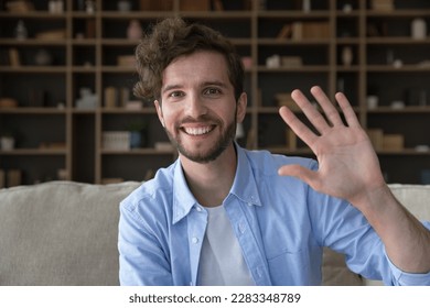 Cheerful handsome young freelance employee man video conference call screen portrait. Happy millennial guy looking at camera, smiling, laughing, waving hand hello. Home head shot - Powered by Shutterstock