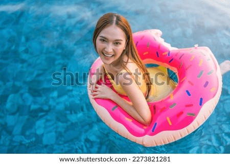 cheerful happiness asian carefree woman playing fun wear yellow two piece swimsuit hold pink inflatable donut ring Summer Vacation. Enjoying suntan Woman in yellow bikini on the inflatable swim pool