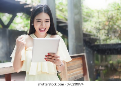 Cheerful Happy Asian Girl Excited Looking At Touch Pad Tablet