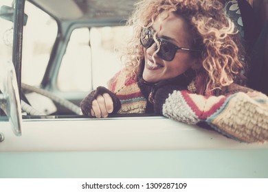 Cheerful happy beautiful caucasian young woman looking and smiling out of the window from old vintage van bus with sunglasses - travel driving concept for cute attractive girl with curly hair - Powered by Shutterstock