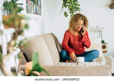 Cheerful and happy beautiful woman at home enjoy a phone call sitting on the sofa - single female people relax in indoor leisure activity alone - happy independent lady concept lifestyle