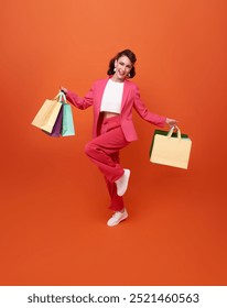Cheerful happy businesswoman enjoying shopping, she is carrying shopping bags and jumping to get the latest offers at the shopping center.