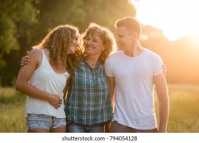 Alegre família caucasiana feliz ao ar livre durante o pôr do sol do verão