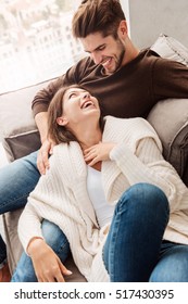 Cheerful Happy Couple In Love Lying On A Couch At Home