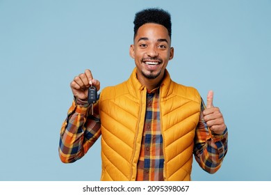 Cheerful happy driver young black man 20s years old wears yellow waistcoat shirt hold in hand new car key showing thumb up like gesture isolated on plain pastel light blue background studio portrait