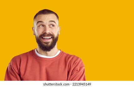 Cheerful happy funny joyful bearded young man in sweatshirt isolated on solid yellow color background looking to blank empty copy space side and smiling - Shutterstock ID 2213945149
