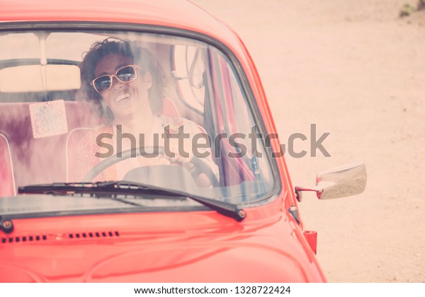Cheerful happy lady caucasian\
middle age curly female smile and laugh driving her old retro\
beautiful car - woman insurance concept for happy people\
traveling