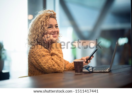Cheerful happy people woman traveler wait at the airport gate for delay flight using modern technology device as phone and laptop computer - defocused background with bokeh