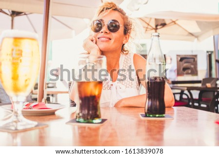 Cheerful happy pretty lady sit down at the restaurant waiting for food or pizza and enjoying a fresh drink - tourism and vacation outdoor leisure activity concept with beautiful woman people